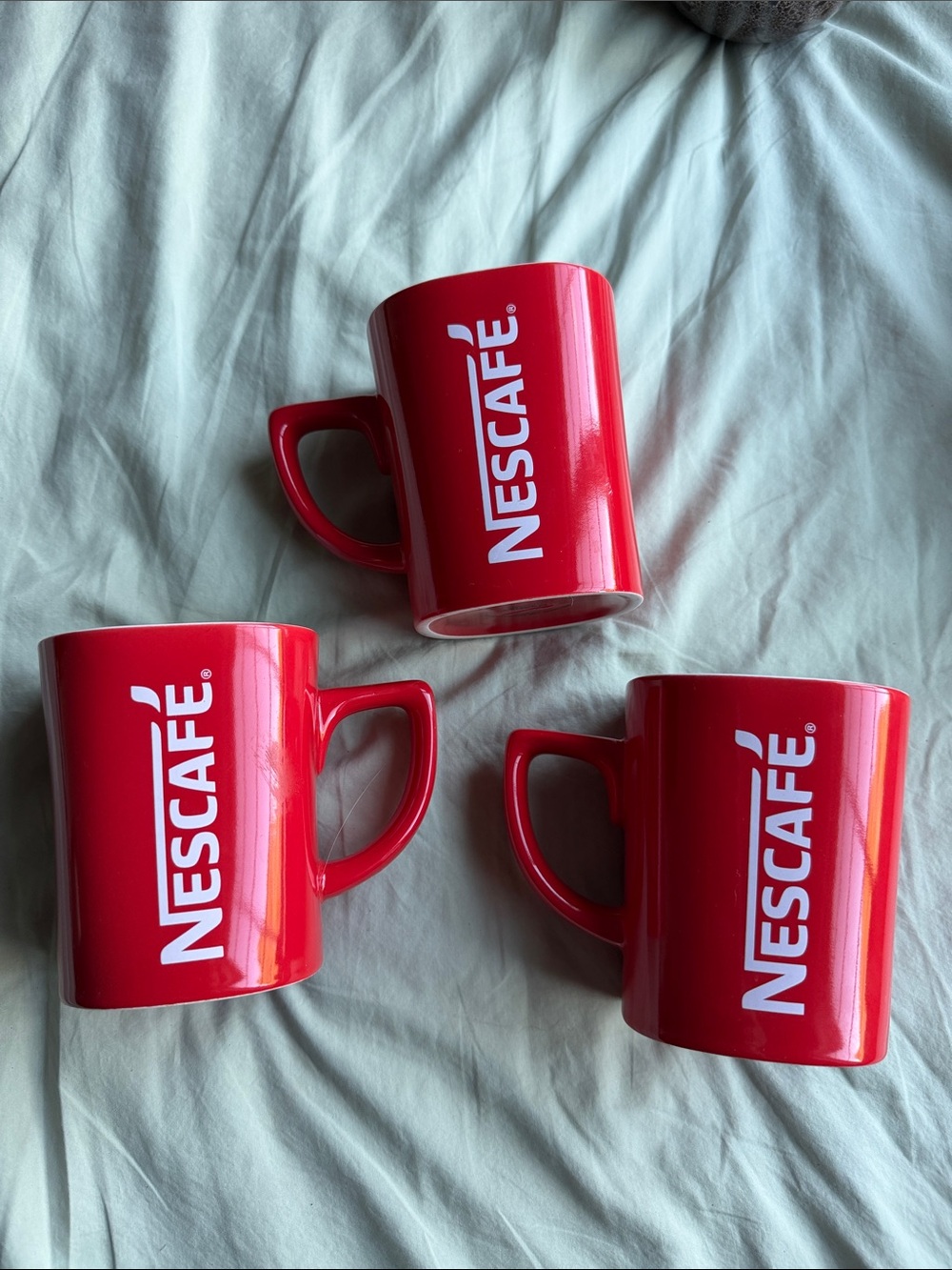 red NESCAFÉ branded ceramic three  mugs with white lettering.